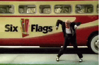 velhinho de terno dançando muito  em frente a um ônibus antigo passando na rua