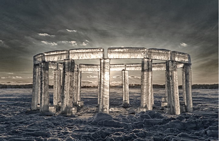 in a vast frozen open landscape an architectural circle of ice blocks resemble the stonehenge and reflect the light of the sun behind